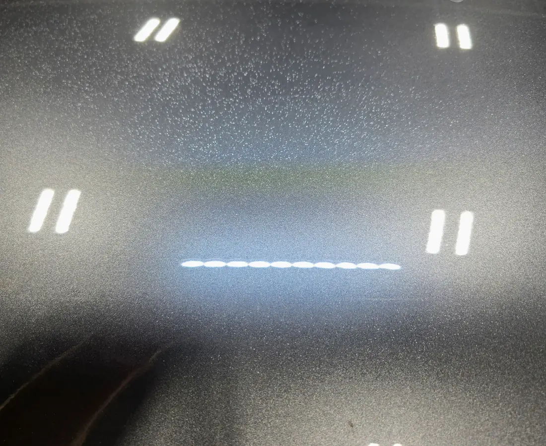 Dark metallic paint under the studio inspection light before an exterior detail