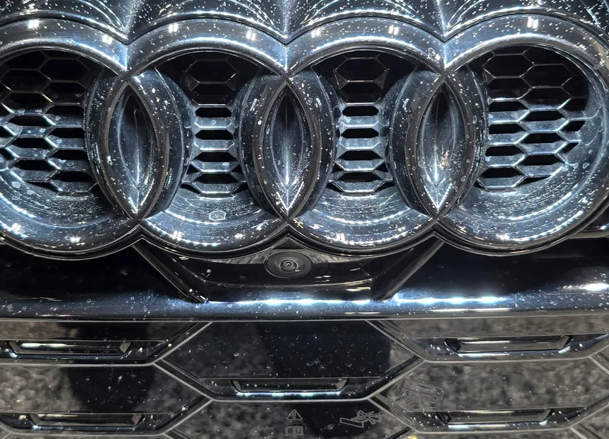 An Audi grille and badge carrying overspray and industrial fallout