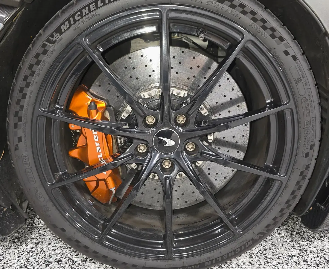 A McLaren wheel and carbon ceramic brake dulled by brake dust and road film before detailing