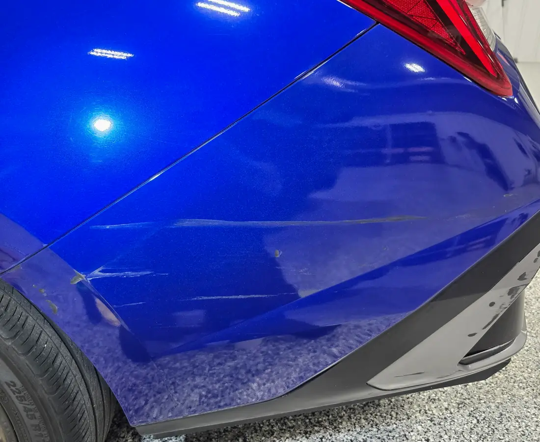The rear quarter panel of a blue Corvette before an exterior detail