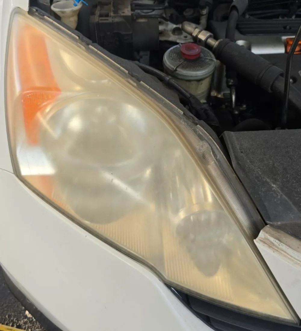 A yellowed, oxidized headlight lens before restoration