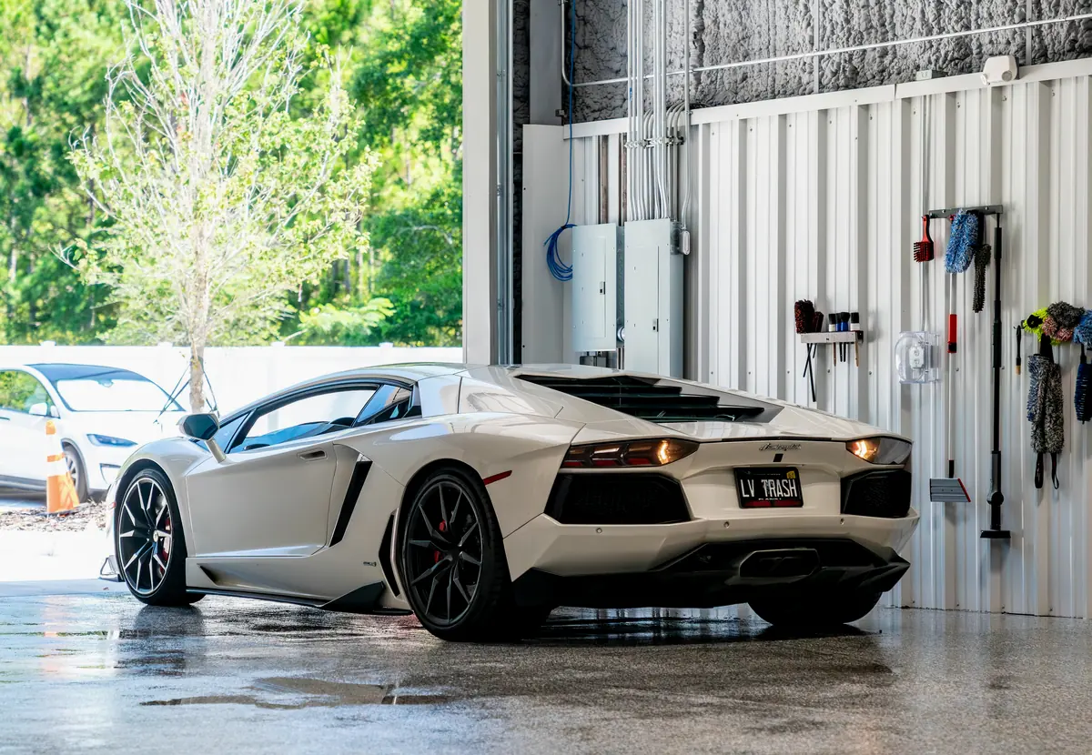 The bay doors open onto Florida greenery with a Lamborghini inside