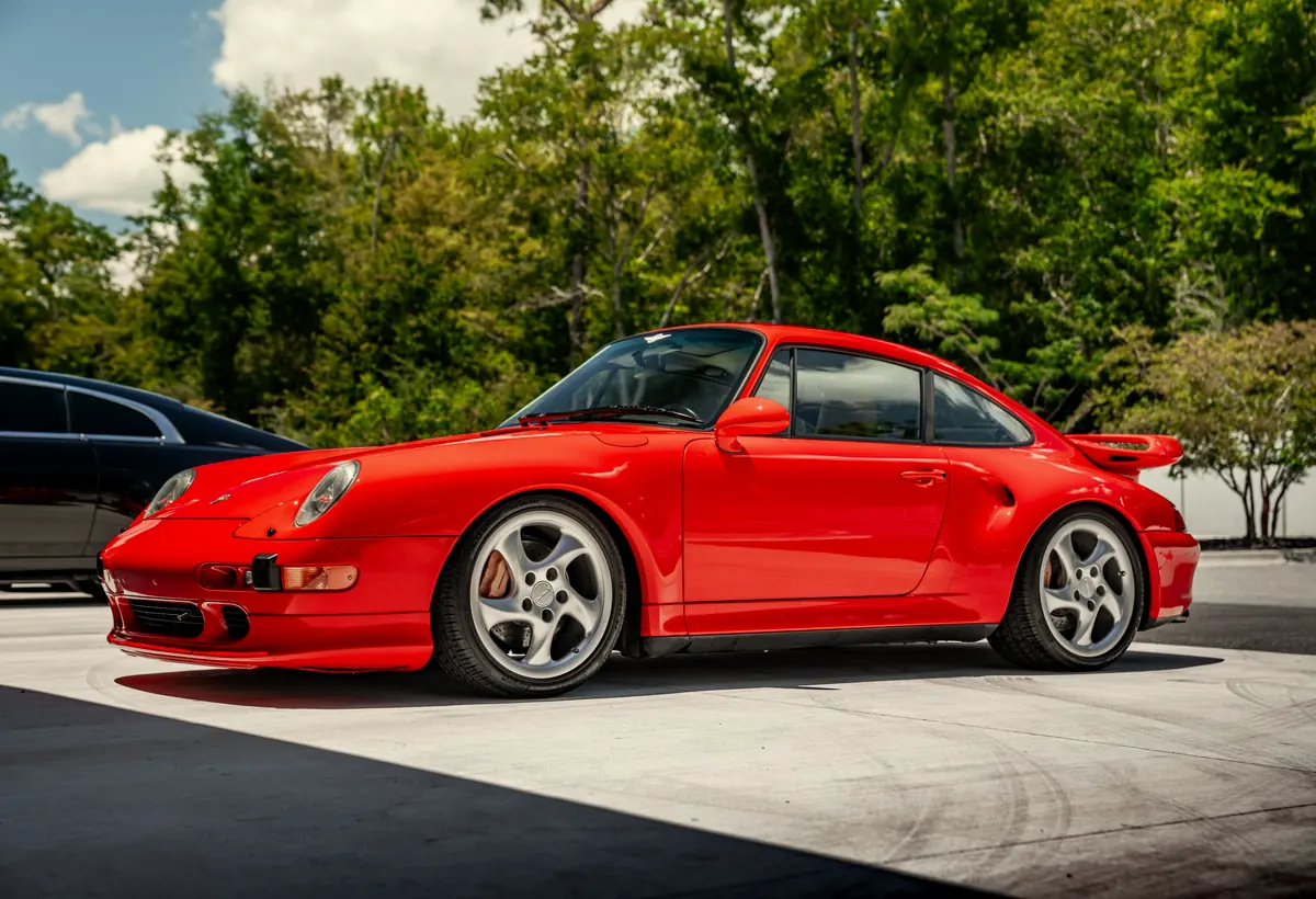 A red Porsche 911 photographed outside among the trees