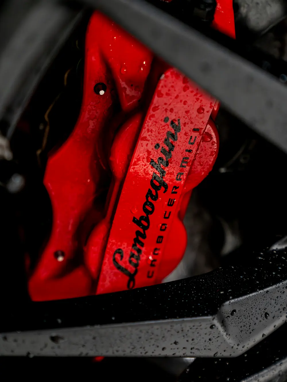 A Lamborghini brake caliper behind the wheel spokes