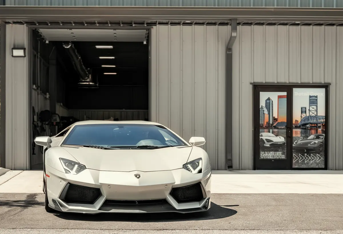 A white Lamborghini parked outside the Detail Geex building