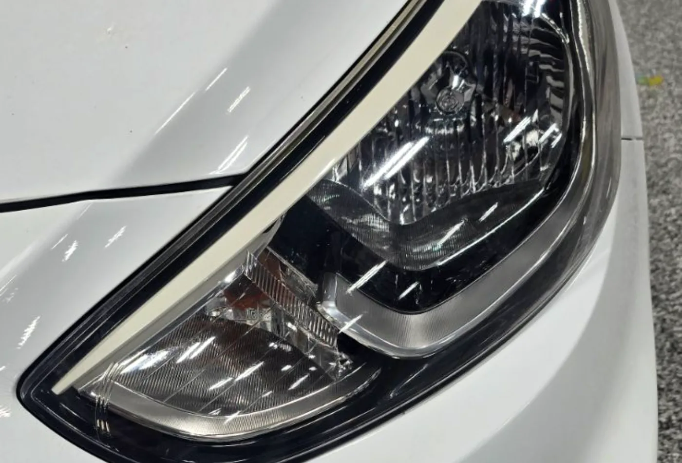 A restored headlight lens on a white car, clear again