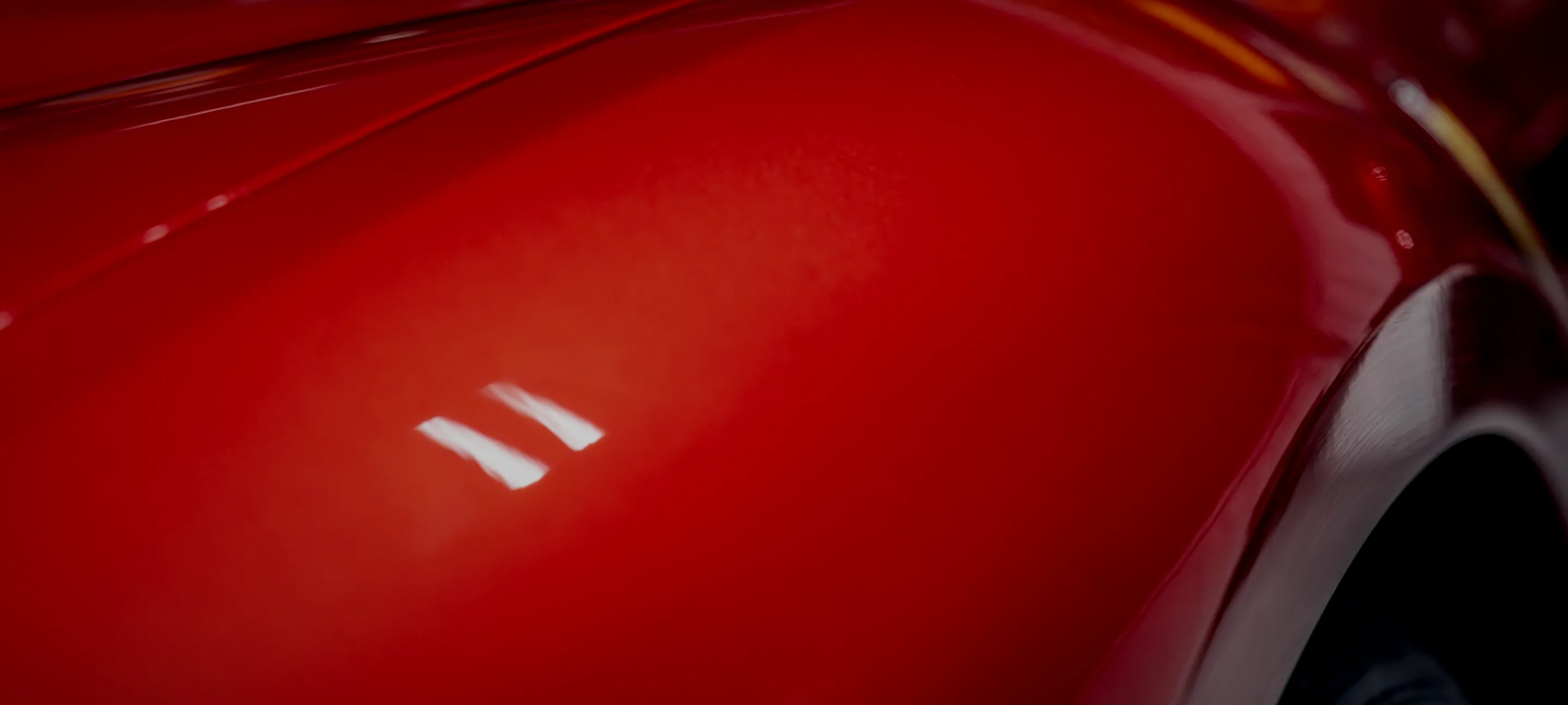 A red Ferrari photographed from the rear three-quarter inside the Detail Geex bay