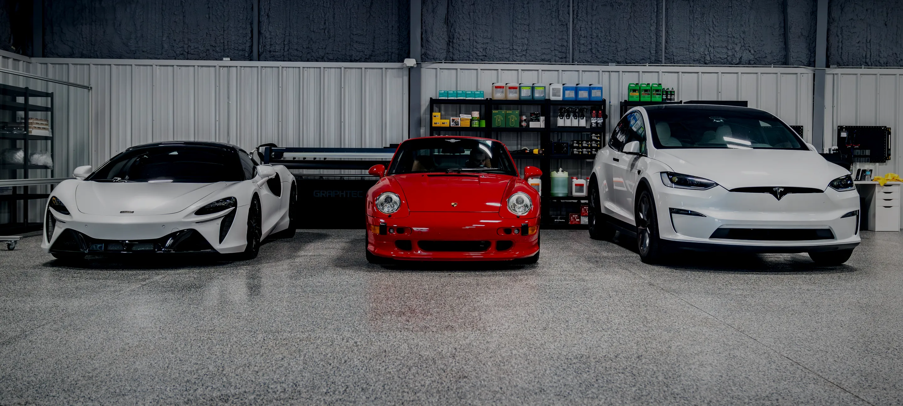 A McLaren, a Porsche 911 and a Tesla waiting inside the Detail Geex bay