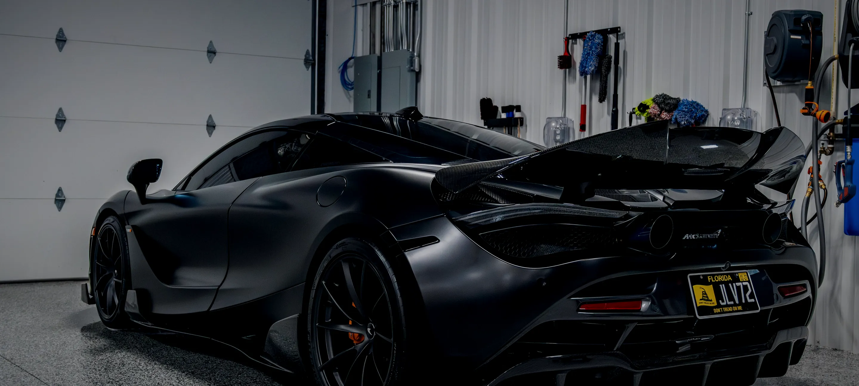 A satin black McLaren alone in the climate-controlled Detail Geex bay