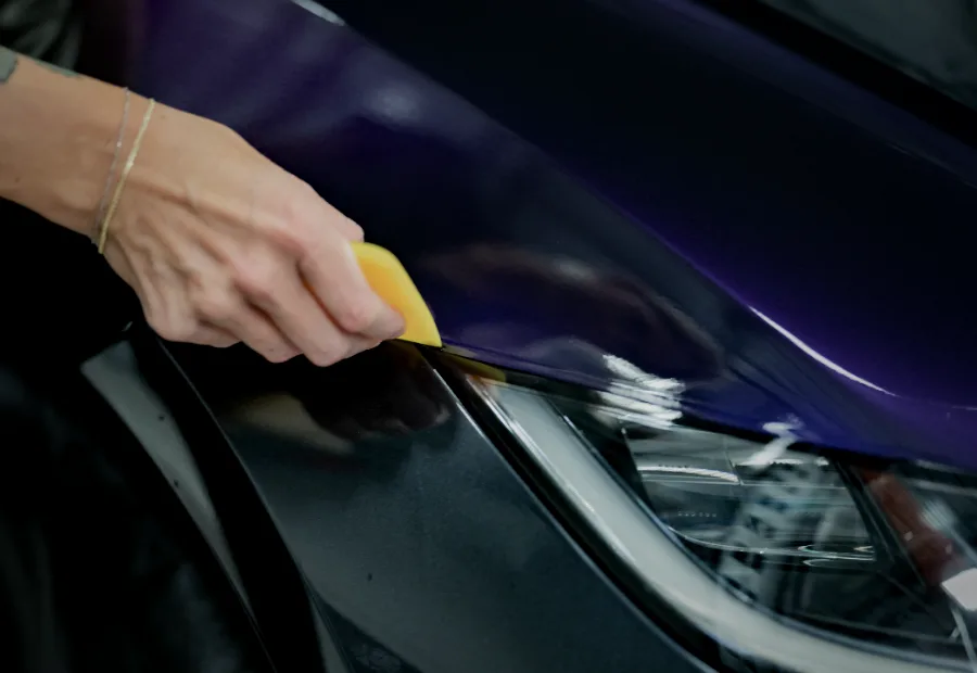 Purple color-change film being squeegeed onto a fender