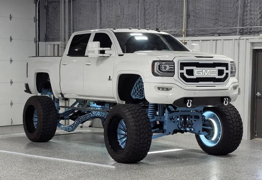 A lifted white GMC Sierra inside the Detail Geex bay
