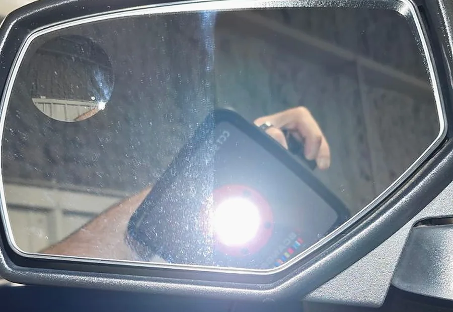 A door mirror under an inspection light on a blue truck